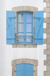 Fenêtre à volets bleus sur une maison de caractère du littoral morbihannais