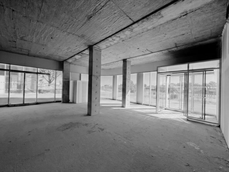 Aménagement intérieur de bureaux dans le Morbihan, volume brut avec poteaux béton et façades vitrées