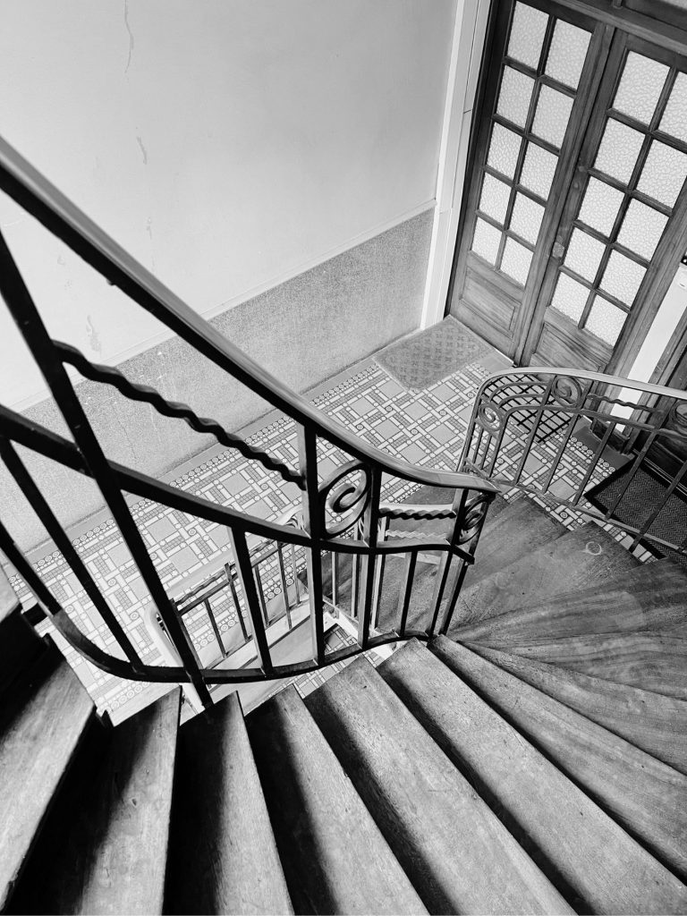 Escalier ancien avec garde-corps en ferronnerie, bois ancien et carreaux de ciment, observé lors d’une visite conseil avant achat