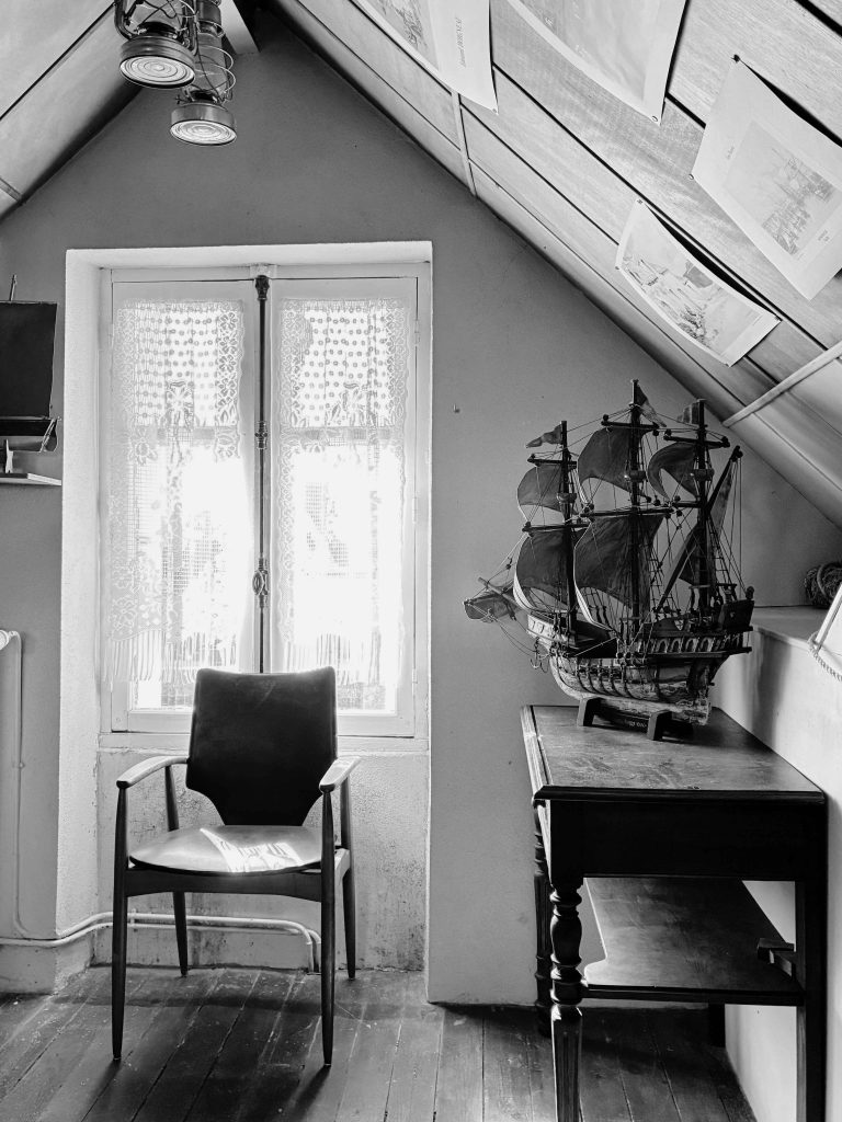 Pièce sous combles avec plancher ancien et charpente apparente dans une maison d'une île du Golfe du Morbihan