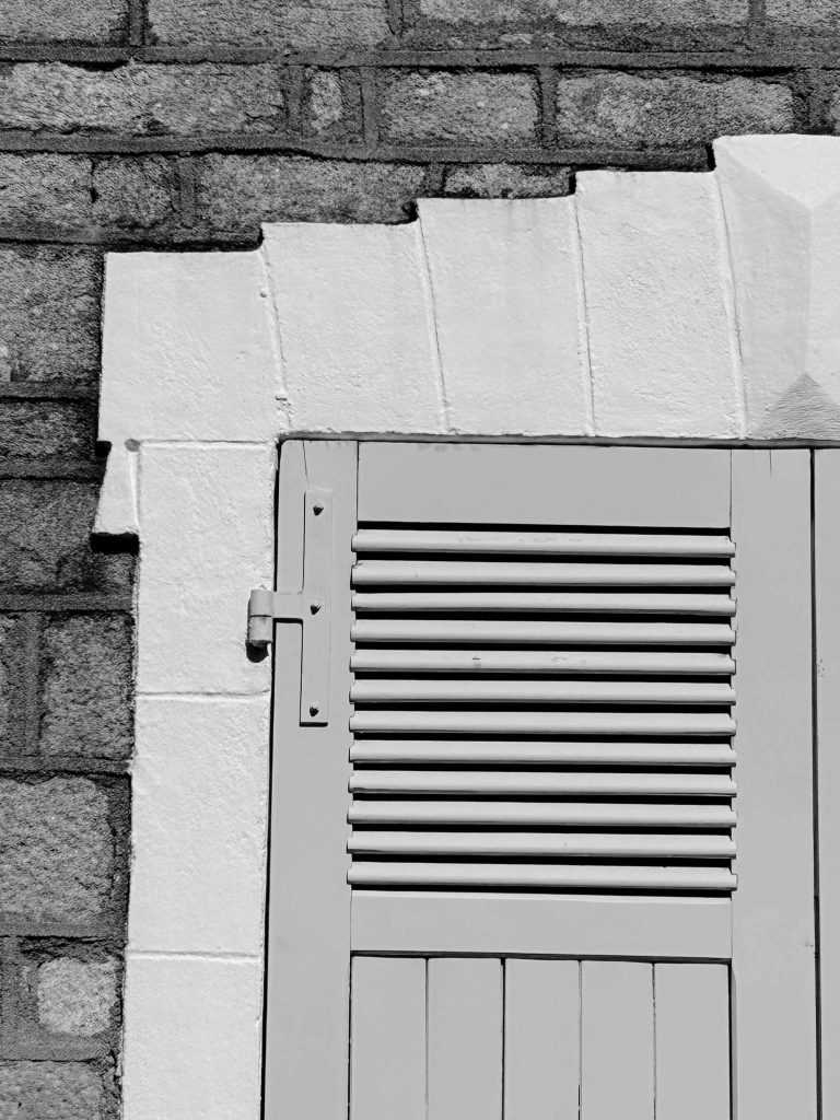 Détail d’un volet ancien et de son encadrement en pierre sur une maison d'une île du Golfe du Morbihan