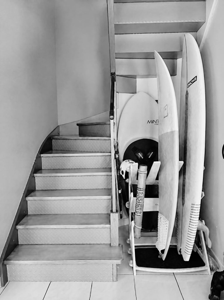 Escalier avec planches de surf dans une maison contemporaine du littoral morbihannais, avant un projet de rénovation intérieure